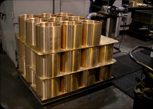 Pallet loaded with finished bronze sleeves stacked in layers inside Magnolia Metal’s machine shop.
