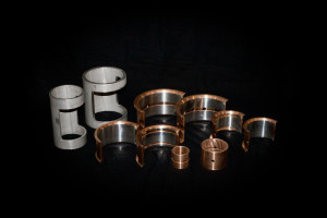 Assorted babbitted bronze bearing shells and bushings displayed on a black background.