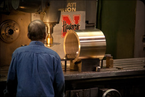 Machinist at a horizontal mill works on a large bronze bearing sleeve clamped on the machine table.