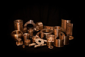 Group of completely finished bronze components including sleeves, flanges, rings, and custom shapes.