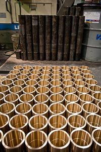 Pallet loaded with finished bronze sleeves stacked in layers inside Magnolia Metal’s machine shop.