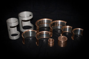 Assorted babbitted bronze bearing shells and bushings displayed on a black background.
