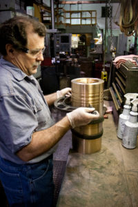 Technician inspects a large machined metal component on a workbench at Magnolia Metal.