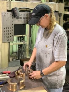 Operator sorts and handles machined metal parts on a workbench inside Magnolia Metal’s production area.